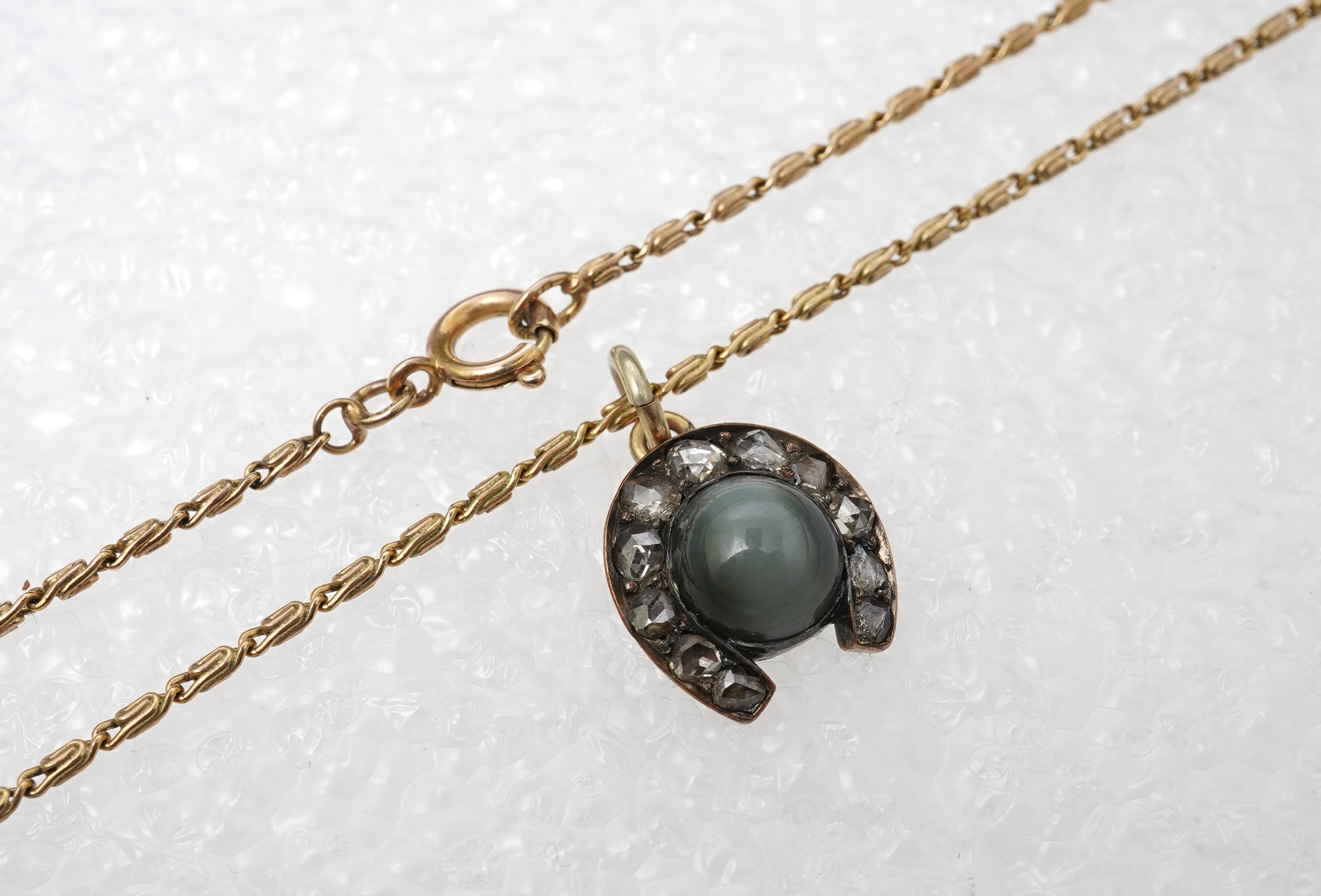 A yellow metal, cat's eye quartz and rose cut diamond cluster set horseshoe pendent, 11mm, together with a 9ct gold chain, 41cm, gross weight 5 grams.